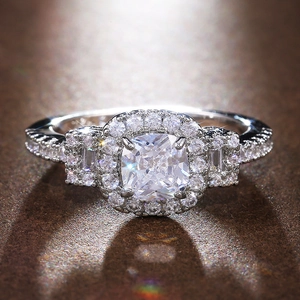 Classic cushion-cut silver ring with micro-pave zircon halo on textured background