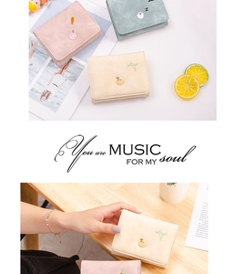 Detail showing cartoon embroidery on colorful pastel wallets with matte texture finish