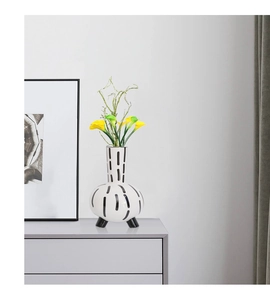 Close-up of modern ceramic vase with hand-painted black stripes and yellow calla lilies
