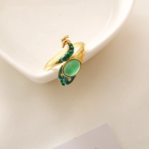 Detail of the golden peacock ring with a green semi-precious stone and enamel feathers