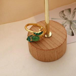 Macro shot of peacock ring details with green gemstone and blue enamel on wooden base