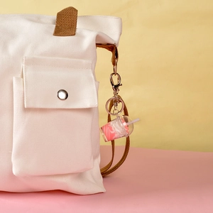 Porte-clés mini gobelet de milk-shake rose avec paille attaché à un sac en toile blanc
