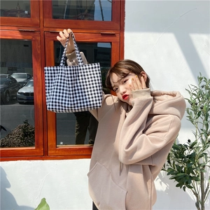 Detail view of a black and white checkered linen handbag held by a person in natural light