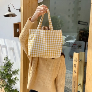 Detailed shot of yellow and white checkered cotton linen tote bag held by a model