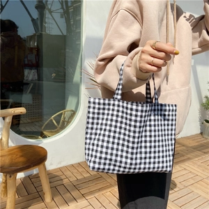 Outdoor close-up of a model holding a black and white checkered cotton linen handbag