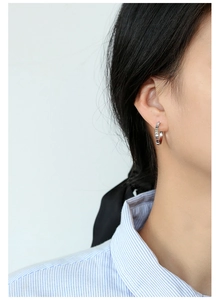 Detailed view of silver hoop earrings with gear pattern on female model ear
