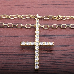 Hip hop gold cross pendant necklace with clear crystals on dark wood background
