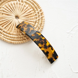 Detailed view of rectangle acetate hair clip with tortoise shell pattern on woven mat