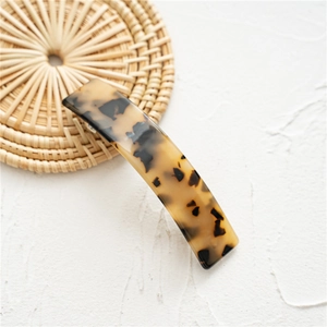 Close-up of tortoise shell pattern acetate hair clip on a natural woven background