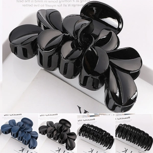 Close-up of black glossy flower hair claw clip with matte blue and textured variants