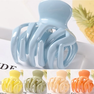 Close-up of large glossy plastic hair claws in blue, yellow, green, cream, and orange