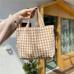 Brown and white checkered canvas handbag with minimalist handle design in sunlight