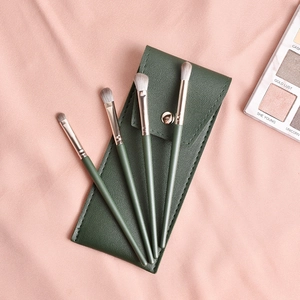 Détail d'un kit de 4 pinceaux de maquillage verts avec embouts dorés et pochette en cuir