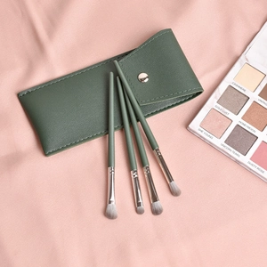 Vue détaillée de quatre pinceaux à paupières verts avec pochette en cuir sur soie rose