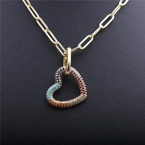 Collier trombone doré avec pendentif cœur en pierres précieuses colorées sur fond sombre