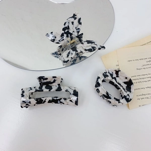 Three acetate hair claws with black and white spotted patterns in various geometric shapes