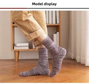 Close-up of thick melange knit crew socks worn on feet in a cozy home setting