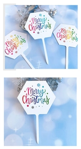 Detailed macro view of white hexagonal Merry Christmas cake toppers with festive patterns