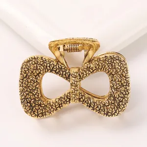 Detail of vintage gold bow hair claw clip with unique hammered metal texture and spring