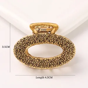 Detailed macro view of gold alloy hair claw with textured finish and spring mechanism