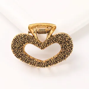Close-up of golden heart claw clip with granular texture and hollowed center design