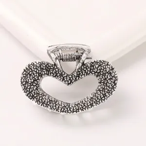 Detail of silver alloy heart hair claw with textured hammer finish and metal spring