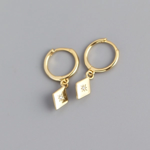 Detail of gold rhombic hoop earrings featuring a starburst engraving and zircon stone