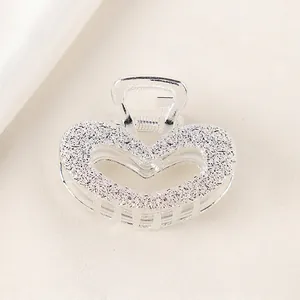 Macro view of silver heart hair claw clip with detailed embossed rose flower texture