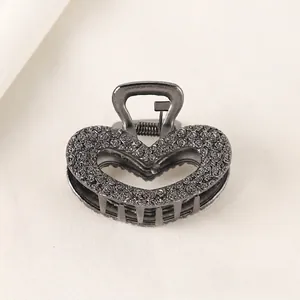 Detailed view of gun black hollow heart hair claw clip with embossed rose pattern