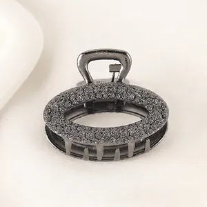 Macro detail of dark grey metal hair claw clip with rose floral embossed texture