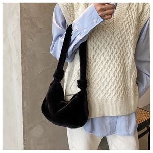 Détail du sac baguette en fourrure noire montrant la texture douce et le nœud décoratif chic