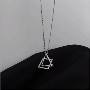 Macro shot of interlocking silver geometric triangle and square pendant on a fine chain