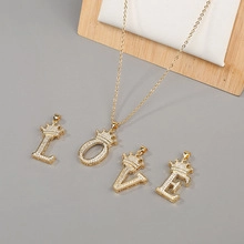 Detail of gold LOVE letter pendants with crowns and sparkling zircon pavé setting