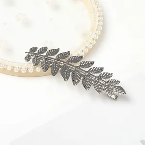 Close-up of silver metal alloy duckbill clip with intricate branch and leaf textures