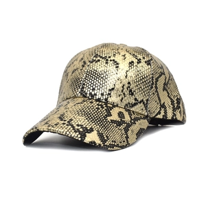 Détail macro de la texture peau de serpent en similicuir doré brillant sur la casquette