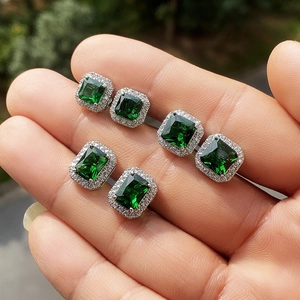 Macro view of three pairs of emerald cut green zircon earrings with halo diamond settings