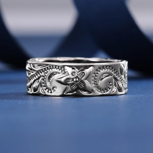 Macro shot of silver ring featuring engraved frangipani flower and leaf patterns