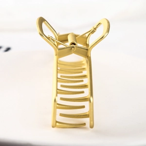 Close-up of matte gold metal hair claw clip with rectangular frame and durable spring