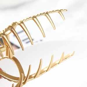 Macro shot of large golden metal hair claw showing textured alloy finish and grip teeth