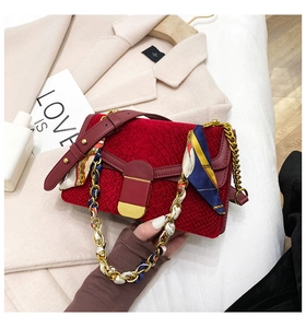Dettaglio della borsa a tracolla in velluto rosso con catena dorata e foulard in seta