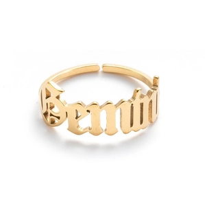 Macro shot of a golden Gemini zodiac ring with vintage lettering on a white background