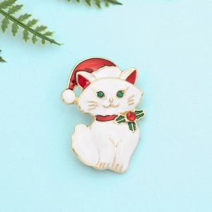 Close-up of a white Christmas cat brooch with a red Santa hat and holly leaf accents
