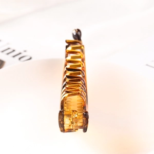 Detailed macro view of an amber acrylic hair claw clip with a durable inner spring mechanism