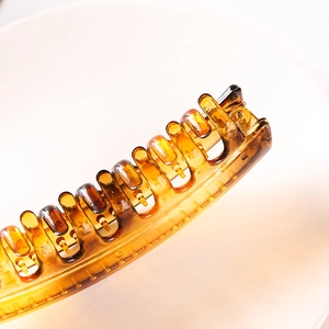 Macro view of amber translucent hair claw clip with smooth teeth and glossy finish