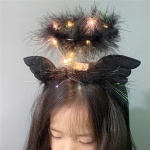 Detail of black feather angel wing headband with glowing LED lights for festive hair accessory