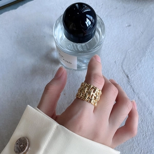 Detailed view of a wide woven gold ring for women on index finger with minimalist style