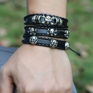 Handmade multilayer black leather bracelet with silver skull charms worn on wrist