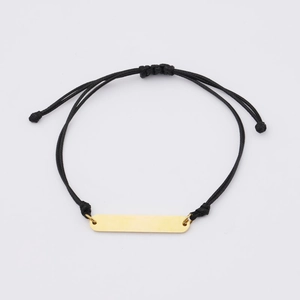 Macro detail of adjustable black braided bracelet with polished gold rectangle bar charm