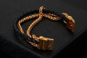Detail of multi-layer men's bracelet with black braided leather and gold wheat chain