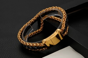Detail of multi-layer gold titanium steel dragon chain and black braided leather bracelet